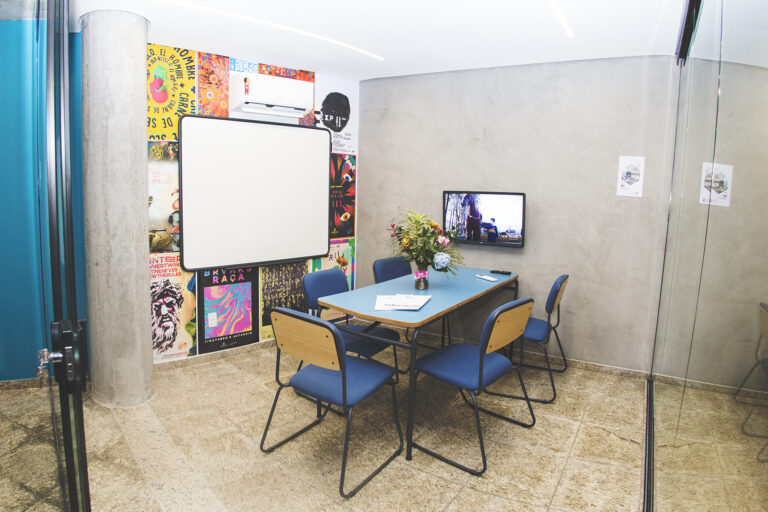 Sala de reunião dentro do coworking Escola Portal, com mesa e cadeiras